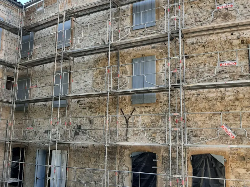 Façade en pierre d'une maison de maître près de Millau sous échafaudage, avant l'enduit à la chaux