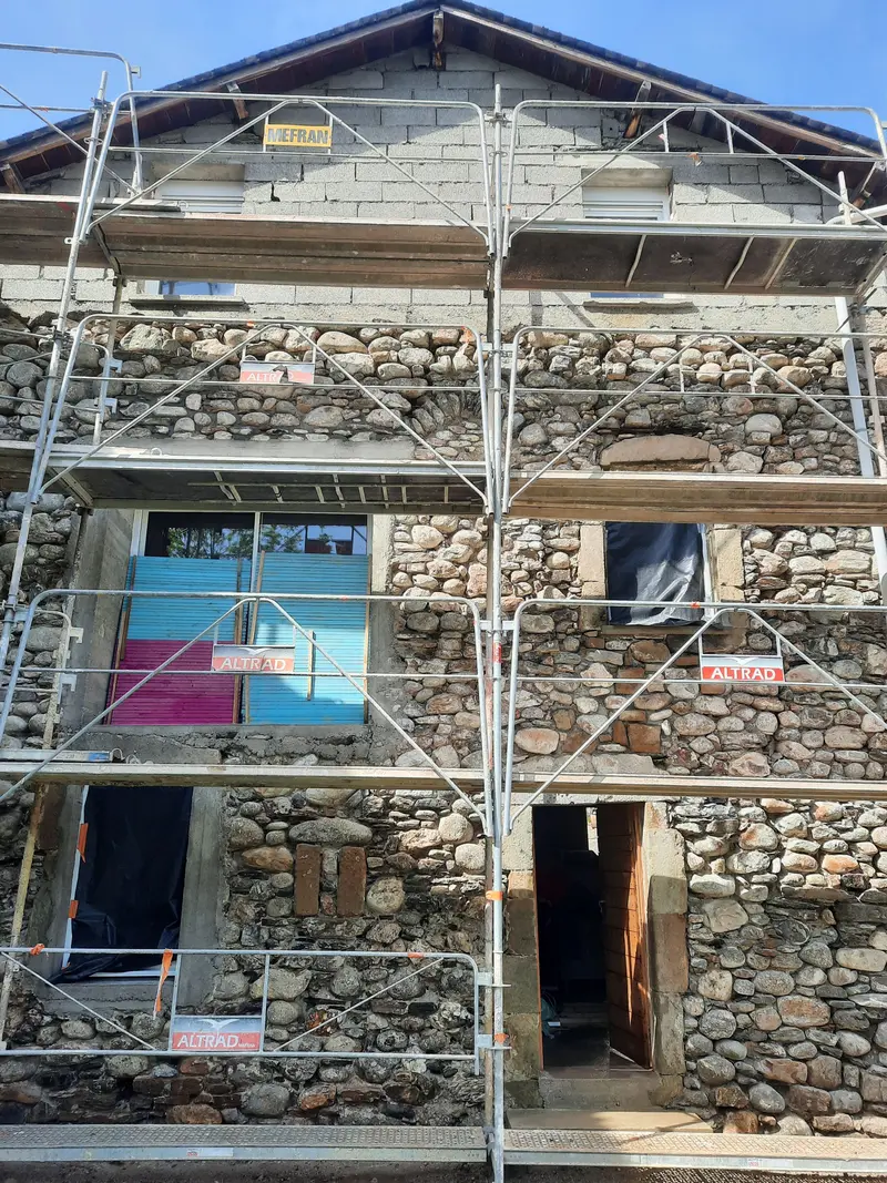 Façade de maison en pierre à moellons ronds à Millau pendant les travaux, pierre mise à nu sous échafaudage
