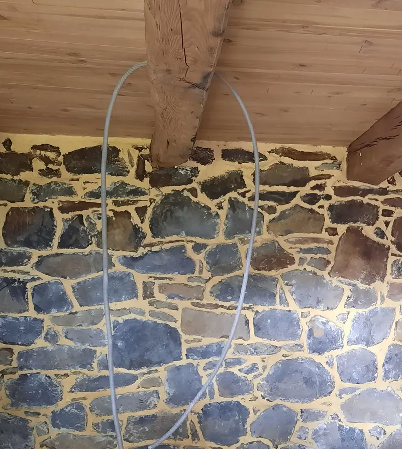 Mur intérieur en pierre apparente sous poutres à Millau, après le rejointoiement à la chaux